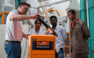 Felix Brooks-church, cofundador de Sanku, explica cómo funciona el dosificador a (de izquierda a derecha) Yeabsra Demle Yimer, gerente del molino; Biruk Teshome, supervisor de fábrica y producción; e Ismael Kassaye, operador de maquinaria. ©Rolex/Aurélie Marrier D’Unienville
